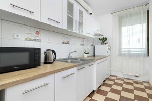 A modern kitchen with white cabinets, a microwave, a kettle, and a sink. - Cracow | Dworska 1B | Functional Apartment | Balcony (Kraków)