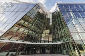 Un bâtiment moderne en verre, doté d’une façade incurvée et d’une entrée centrale.
