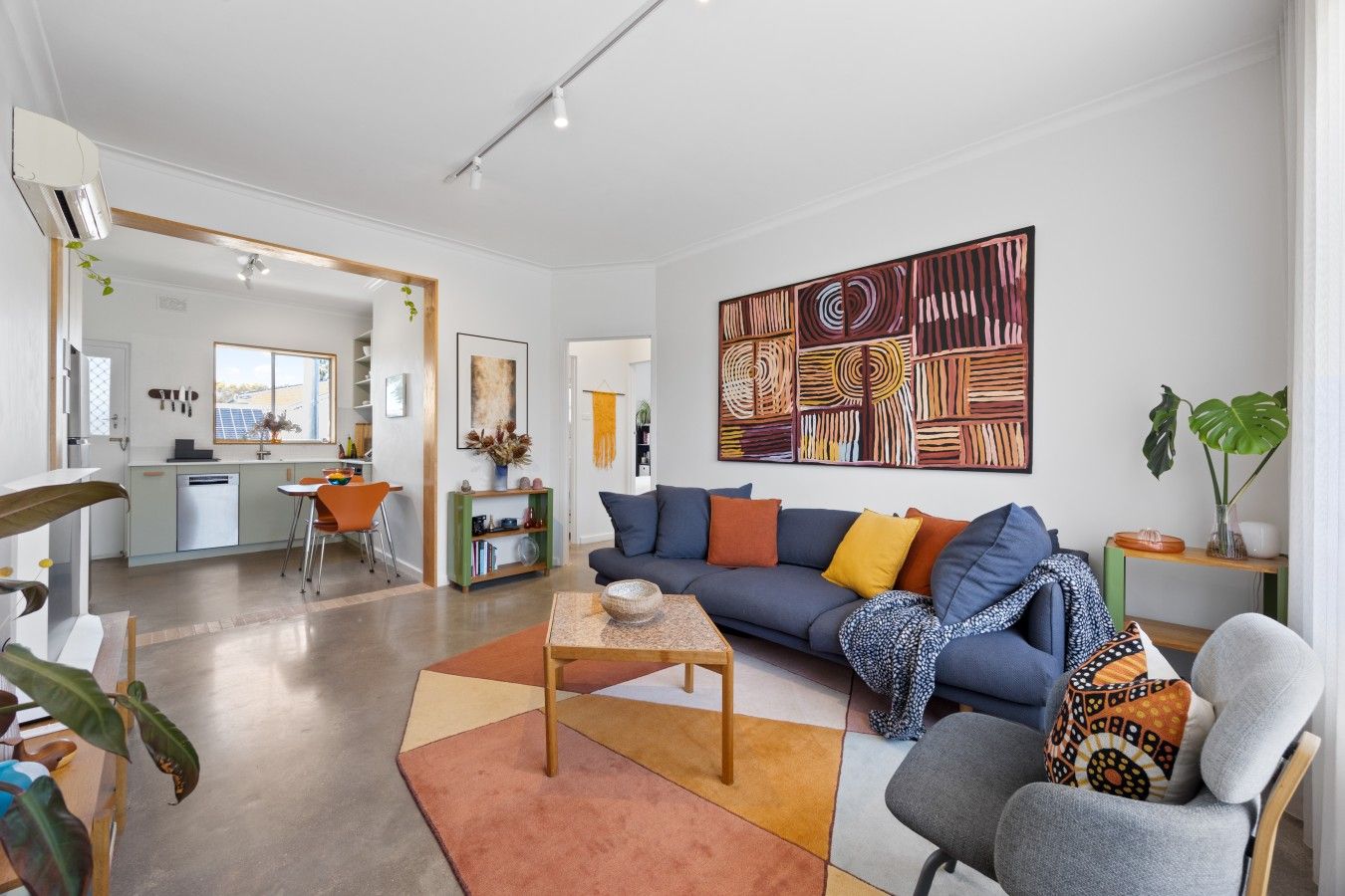 A modern living room with a sofa, coffee table, and a large abstract painting.