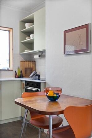 Eine Küche mit Tisch und Stühlen, einer Obstschale und einem gerahmten Bild an der Wand.
