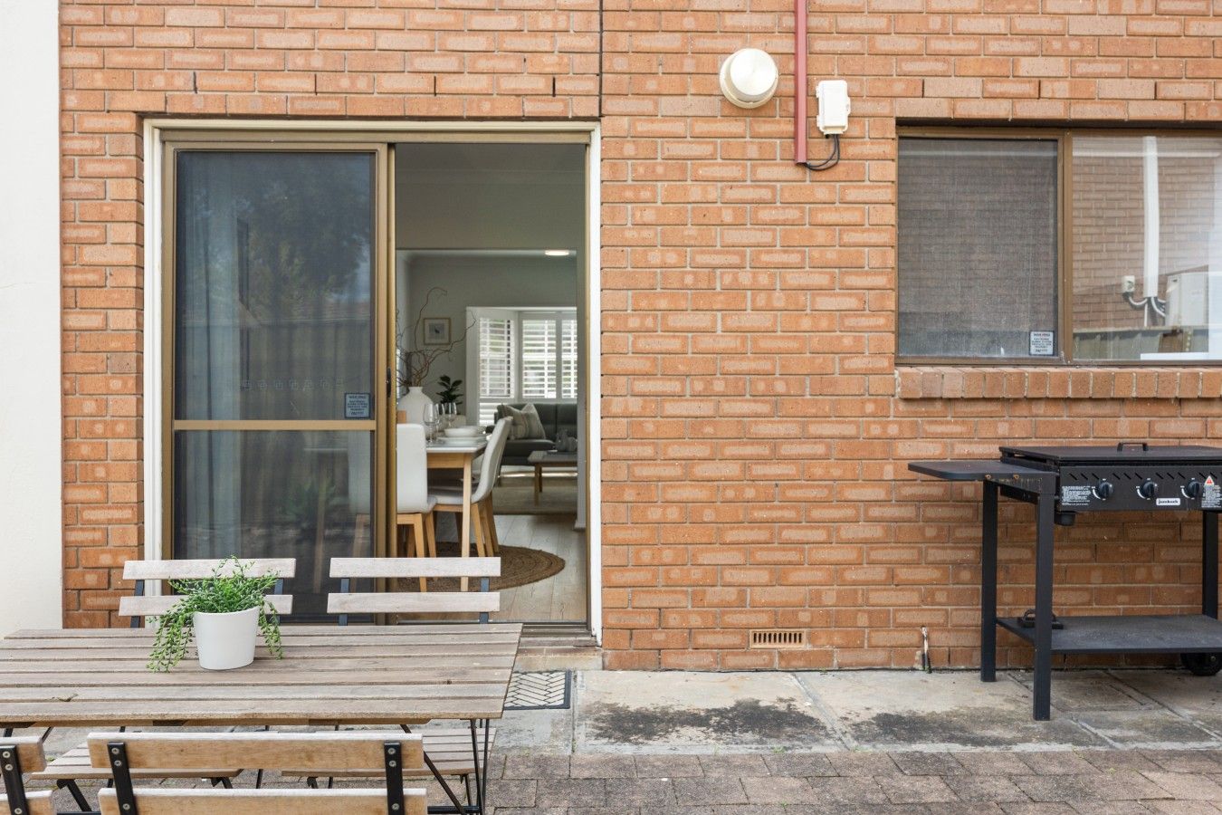 A brick building with a sliding glass door leading to an interior space.