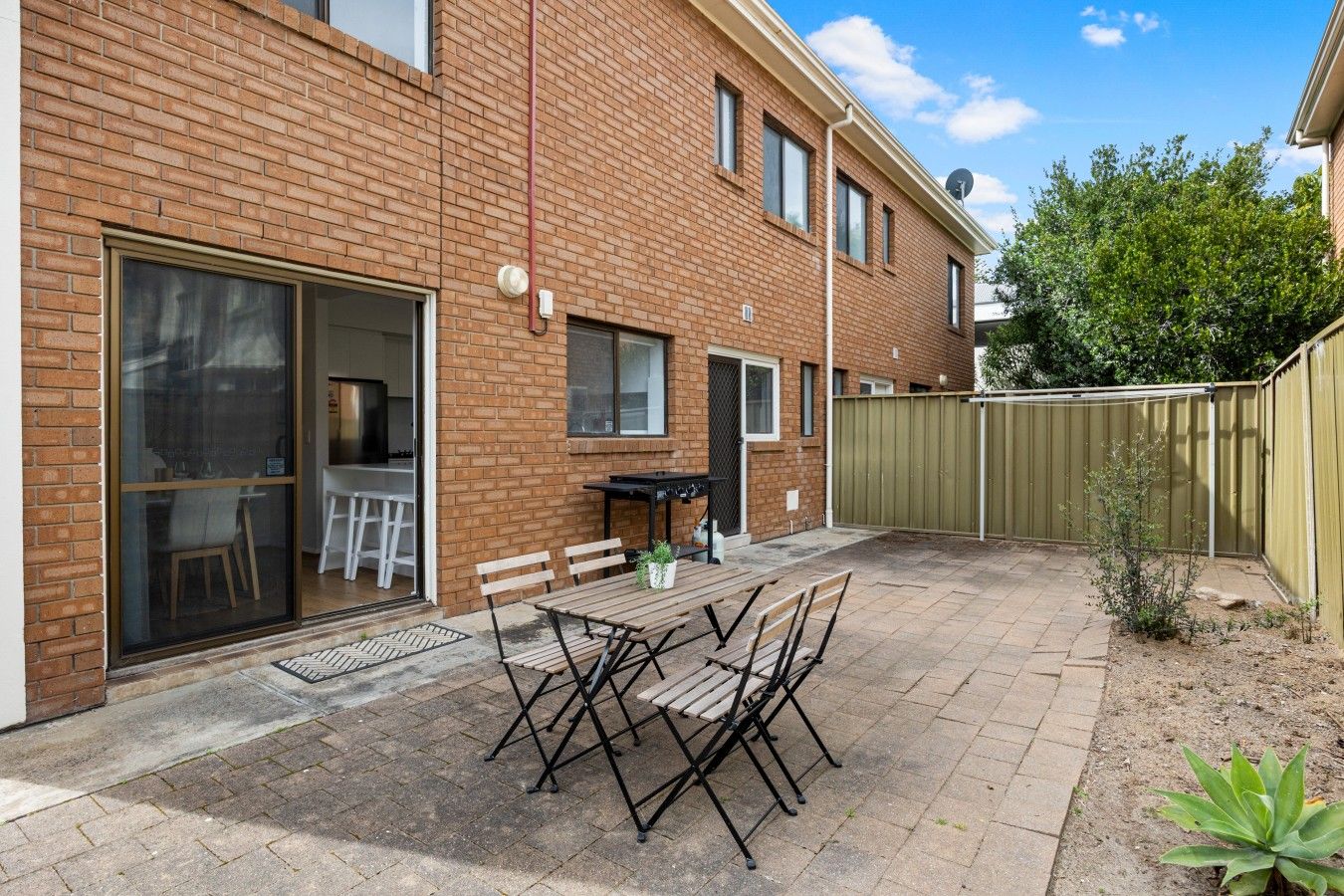 A brick house with a patio, a sliding glass door, and a fenced backyard.