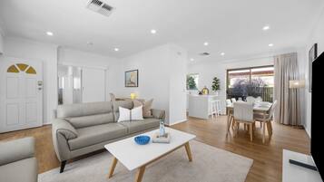 A modern living room with a sofa, coffee table, and dining area with chairs and a table.