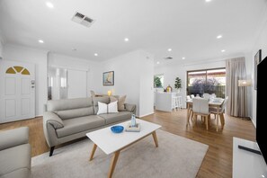 Ein modernes Wohnzimmer mit Sofa, Couchtisch und Essbereich mit Stühlen und einem Tisch.