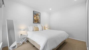 Een hotelkamer met een bed, nachtkastjes, een spiegel en een schilderij aan de muur.