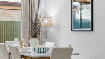 A dining area with a round table, white chairs, and a framed picture on the wall.