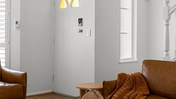A modern living room with a white coffee table, a brown leather sofa, a brown knitted throw, and a blue sculpture.