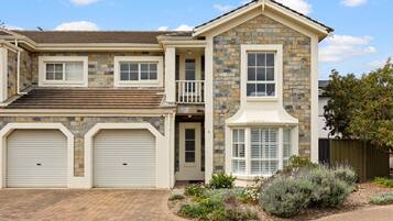 A two-story house with a stone facade, a garage, and a landscaped garden.