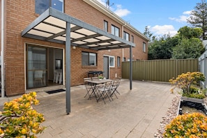 Eine Terrasse mit Tisch und Stühlen, einem Grill und einem überdachten Bereich.