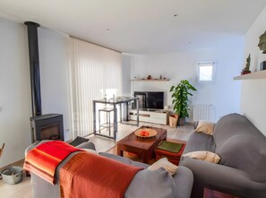 Uma sala de estar moderna com lareira, sofá, TV e área de jantar.