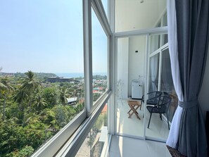 A balcony with a view of a coastal city, a water dispenser, and a chair. - A7 - Luxurious 64 sqm Serviced Apartment Near Karon Beach (Tambon Karon)