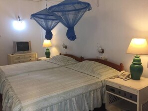 Una cama doble con dosel, lámparas de noche, teléfono en la mesita y una pequeña mesa con lámpara.
