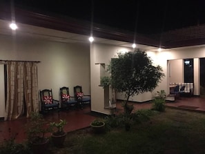 Un área de estar al aire libre con sillas y mesas, una planta en maceta y un árbol.