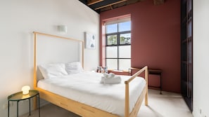 A single bed with a wooden frame, white bedding, and a small bedside table with a lamp. - Myrtle House Loft - City Views & Amazing Rooftop (Chippendale)