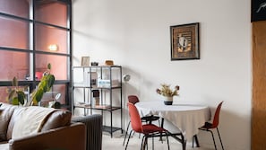 A cozy room with a leather sofa, a dining table with chairs, a bookshelf, and a potted plant. - Myrtle House Loft - City Views & Amazing Rooftop (Chippendale)
