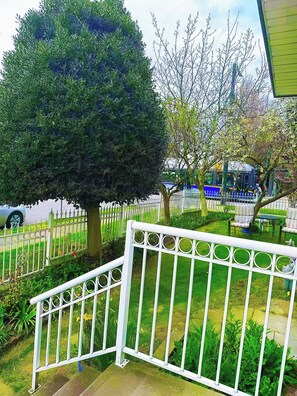 Un jardín cercado con un árbol, una banca y una mesa.
