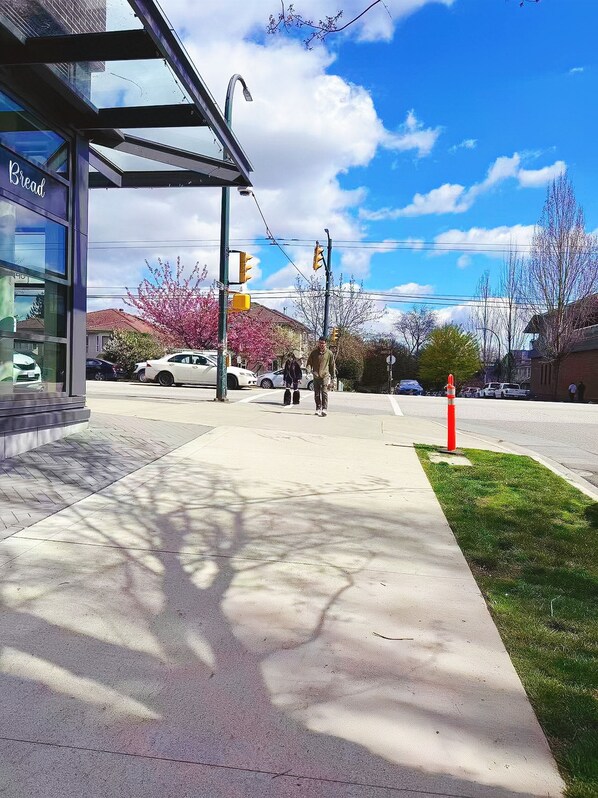 A pedestrian crossing with traffic lights, a sidewalk, and a building with a sign that reads 'Bread.'