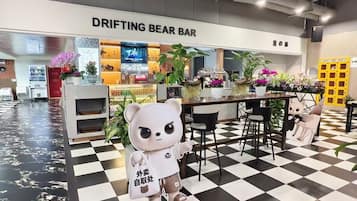 Un bar con suelo a cuadros, un logotipo de oso y un letrero que dice 'DRIFTING BEAR BAR'.