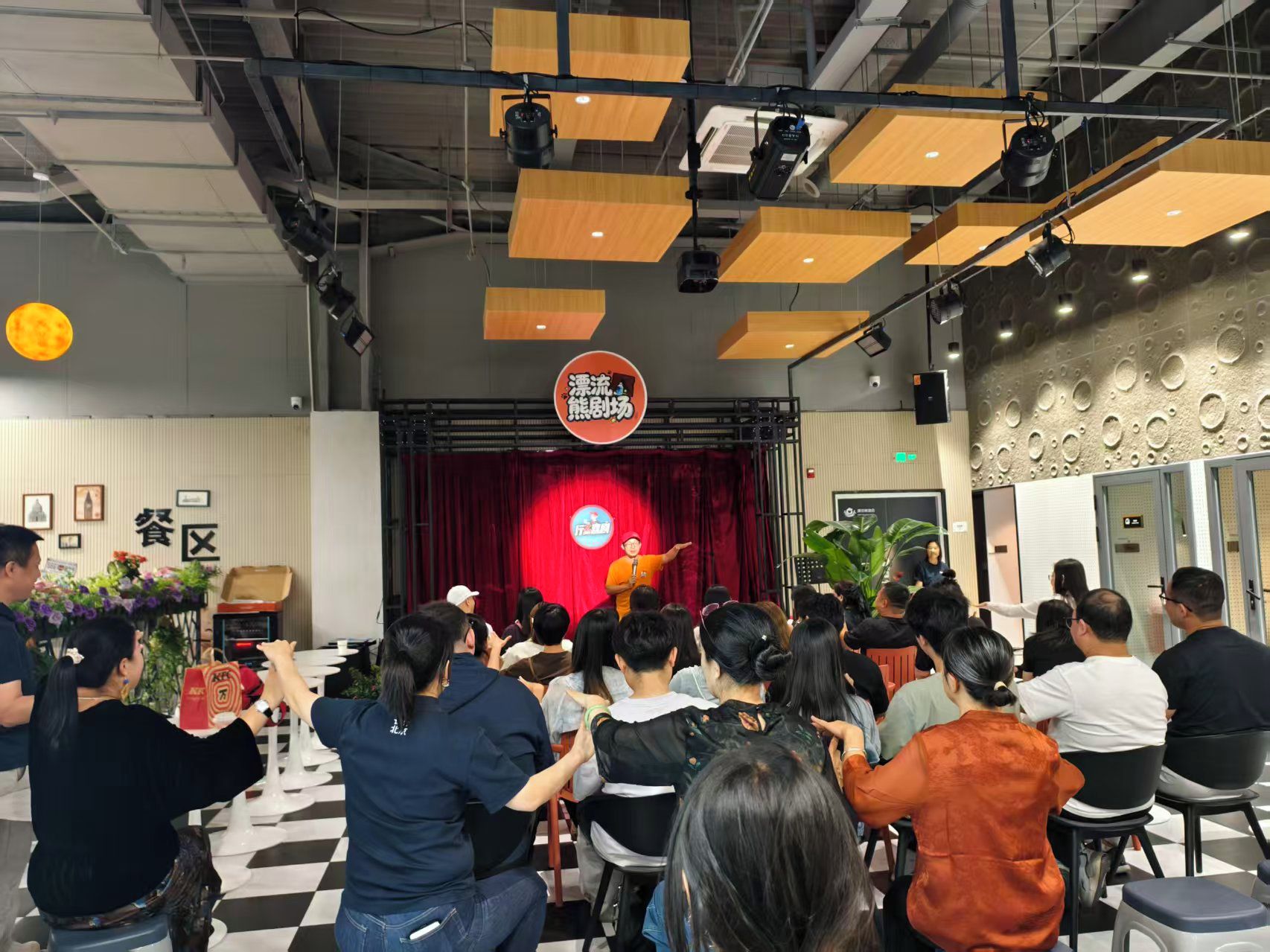 A conference room with a stage, audience seating, and a red curtain backdrop.
