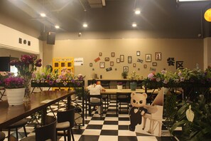 Interior de restaurante con suelo a cuadros, mesas, sillas y diversas decoraciones en las paredes, incluyendo cuadros y letreros.