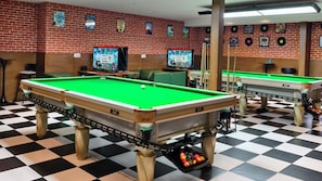 A pool hall with two pool tables, checkered flooring, and a brick wall with posters. - DRIFTING BEAR HOTEL- Sijiqing Qiao Metro (Beijing)