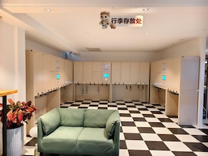 A restroom with multiple towel dispensers, a green sofa, and a checkered floor. - DRIFTING BEAR HOTEL- Sijiqing Qiao Metro (Beijing)
