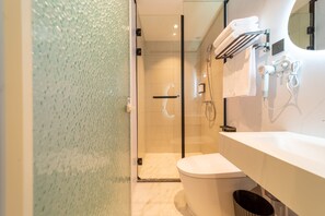 Une salle de bain moderne avec une douche à parois de verre, des toilettes blanches et un meuble-lavabo avec un miroir et un porte-serviettes.