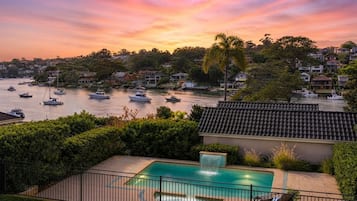 A residential area with a swimming pool, boats on the water, and houses in the background.