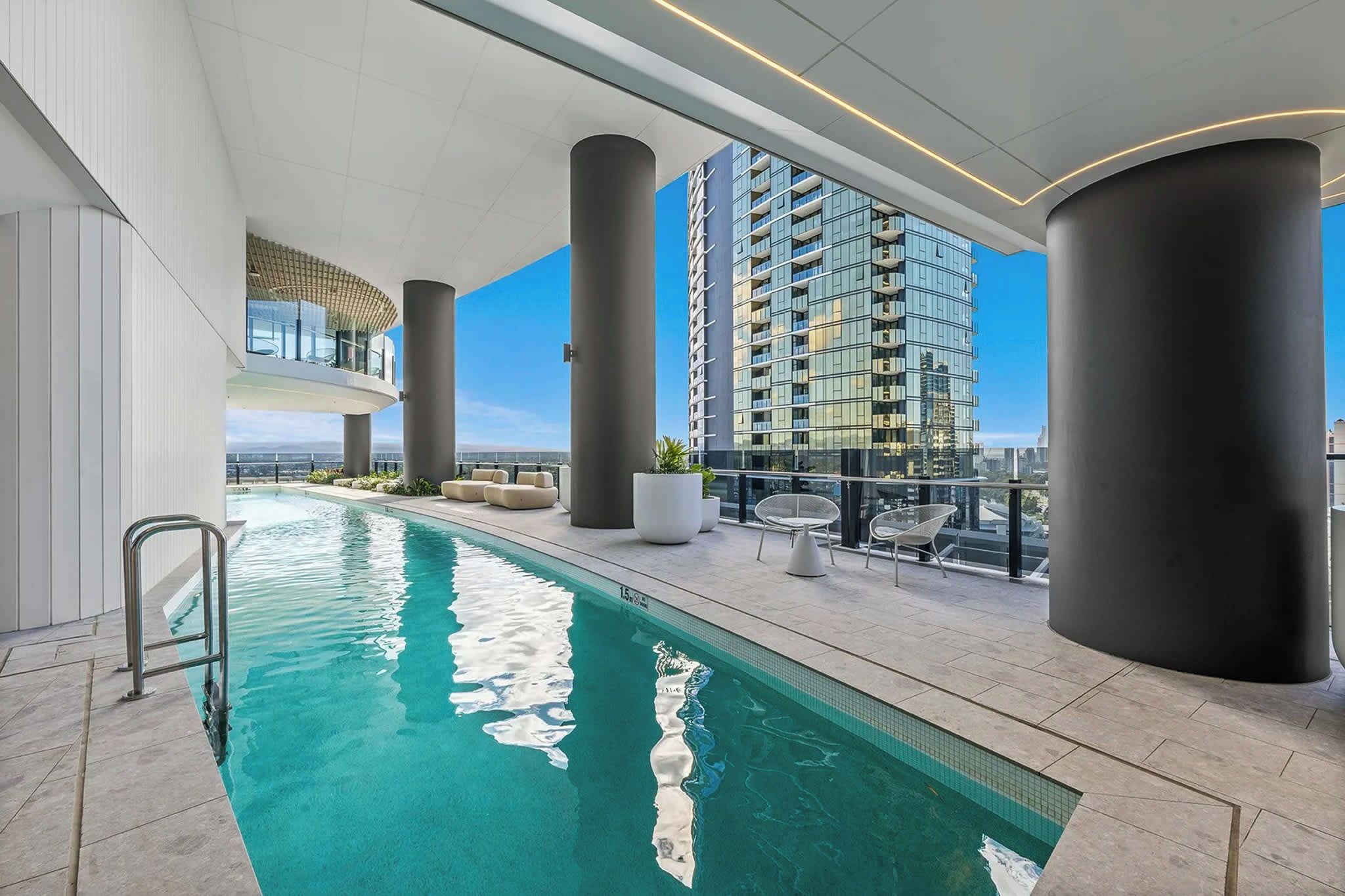 A rooftop swimming pool with a clear view of a high-rise building in the background.