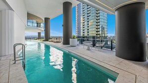 A rooftop swimming pool with a clear view of a high-rise building in the background. - Luxury Broadbeach Ocean View 1 Bedroom with Pool (Broadbeach)