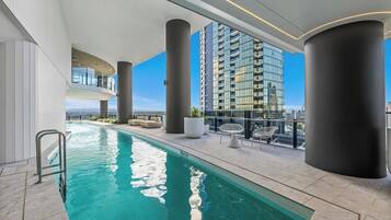 A rooftop swimming pool with a clear view of a high-rise building in the background.