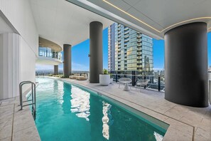 A rooftop swimming pool with a clear view of a high-rise building in the background. - Luxury Broadbeach Ocean View 1 Bedroom with Pool (Broadbeach)