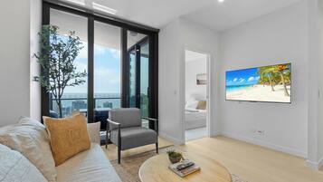 Stylish lounge with King Sofa Bed, Smart TV and floor-to-ceiling glass opening towards the private balcony and Gold Coast ocean skyline.
