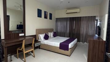 A hotel room with a bed, desk, chair, and a large mirror.