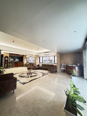Recepció d'hotel amb taulell, sofàs i plantes en testos.