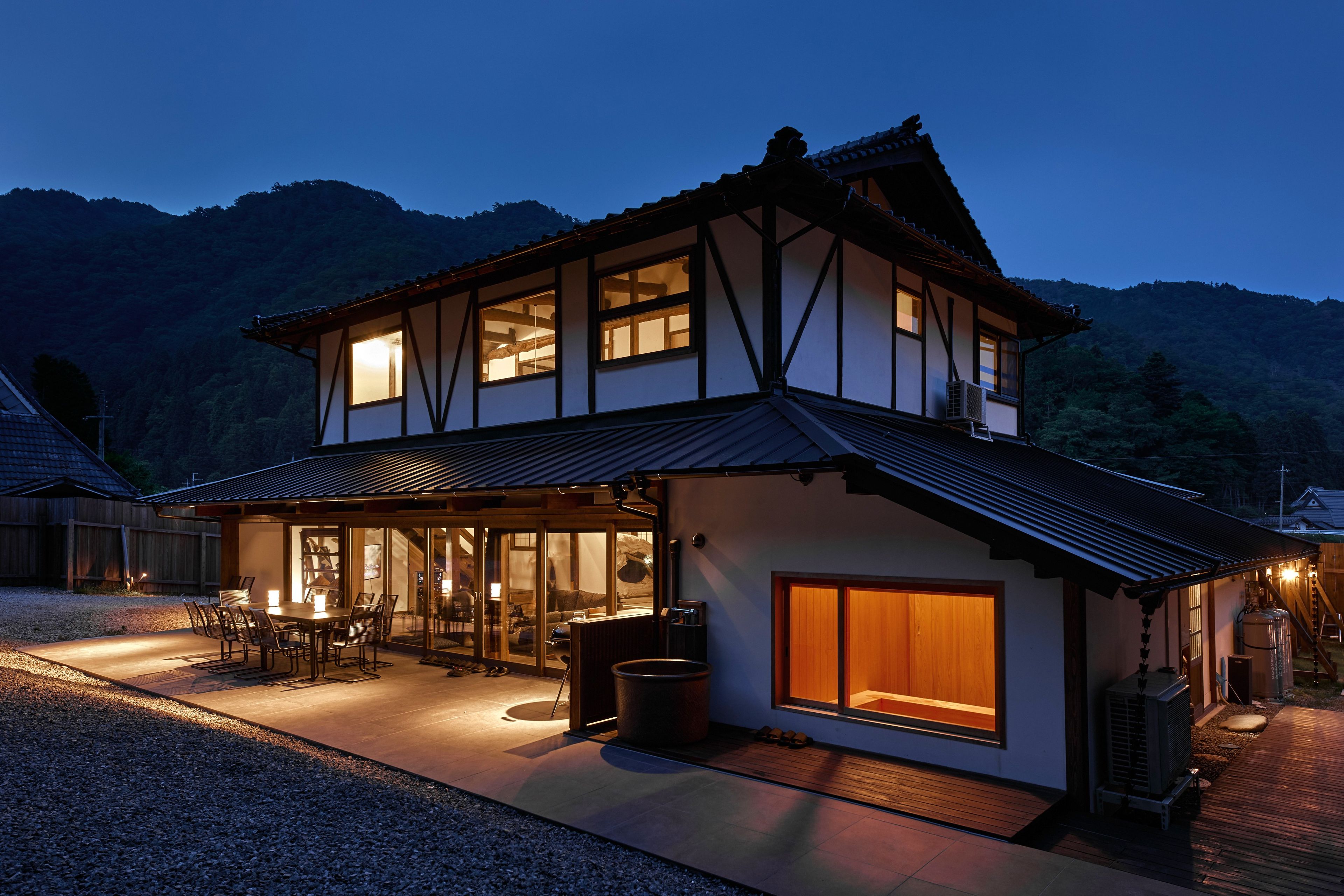 A two-story house with a traditional architectural style, featuring a large window and a covered patio area.