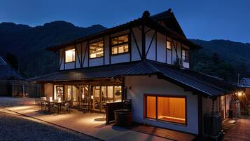 A two-story house with a traditional architectural style, featuring a large window and a covered patio area.