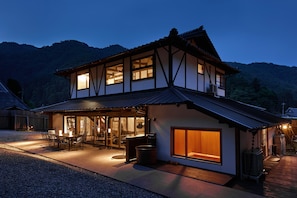 A two-story house with a traditional architectural style, featuring a large window and a covered patio area.