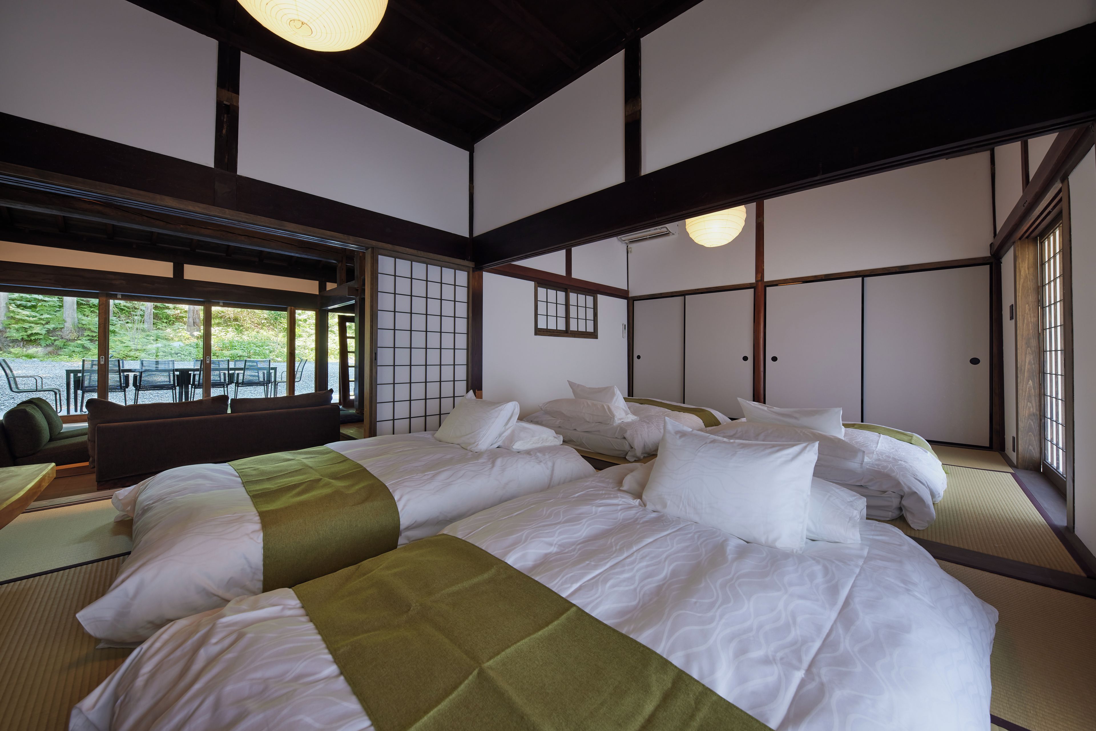 A traditional Japanese-style room with tatami flooring, a large bed with multiple pillows, and sliding doors.