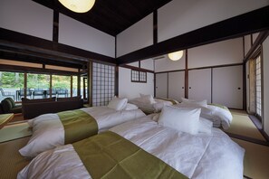 Una habitación al estilo japonés tradicional, con suelo de tatami, una cama grande con muchas almohadas y puertas correderas.