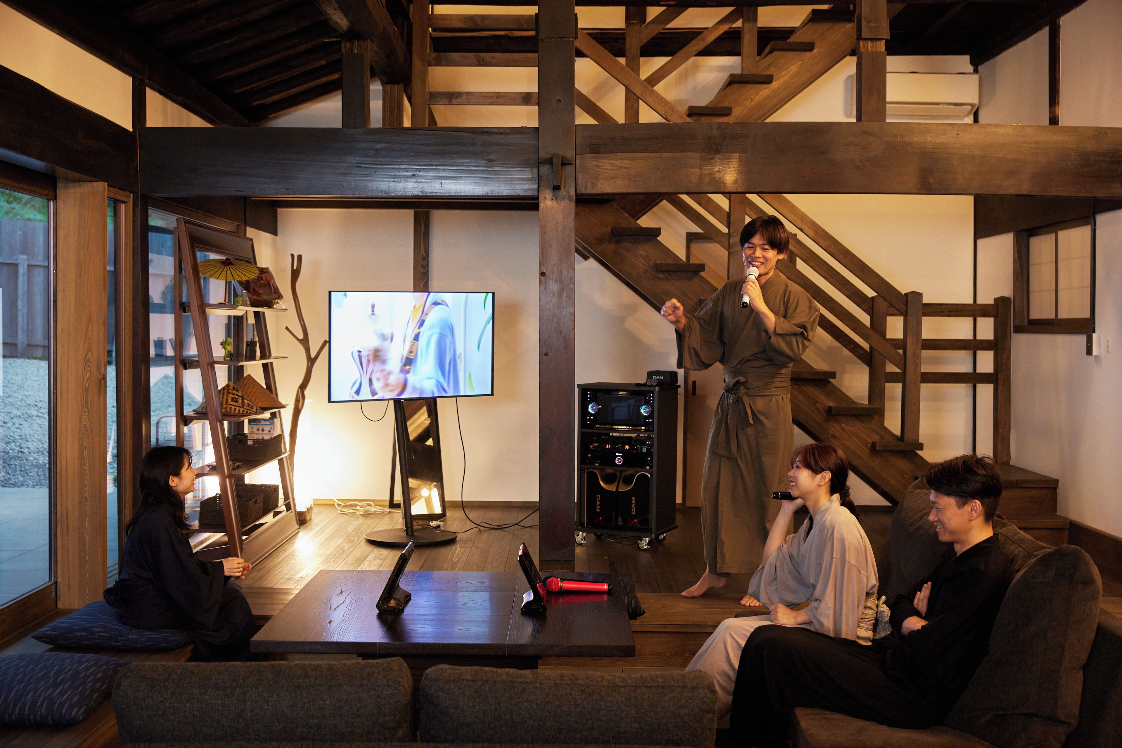 A room with a television, a speaker system, and a staircase.