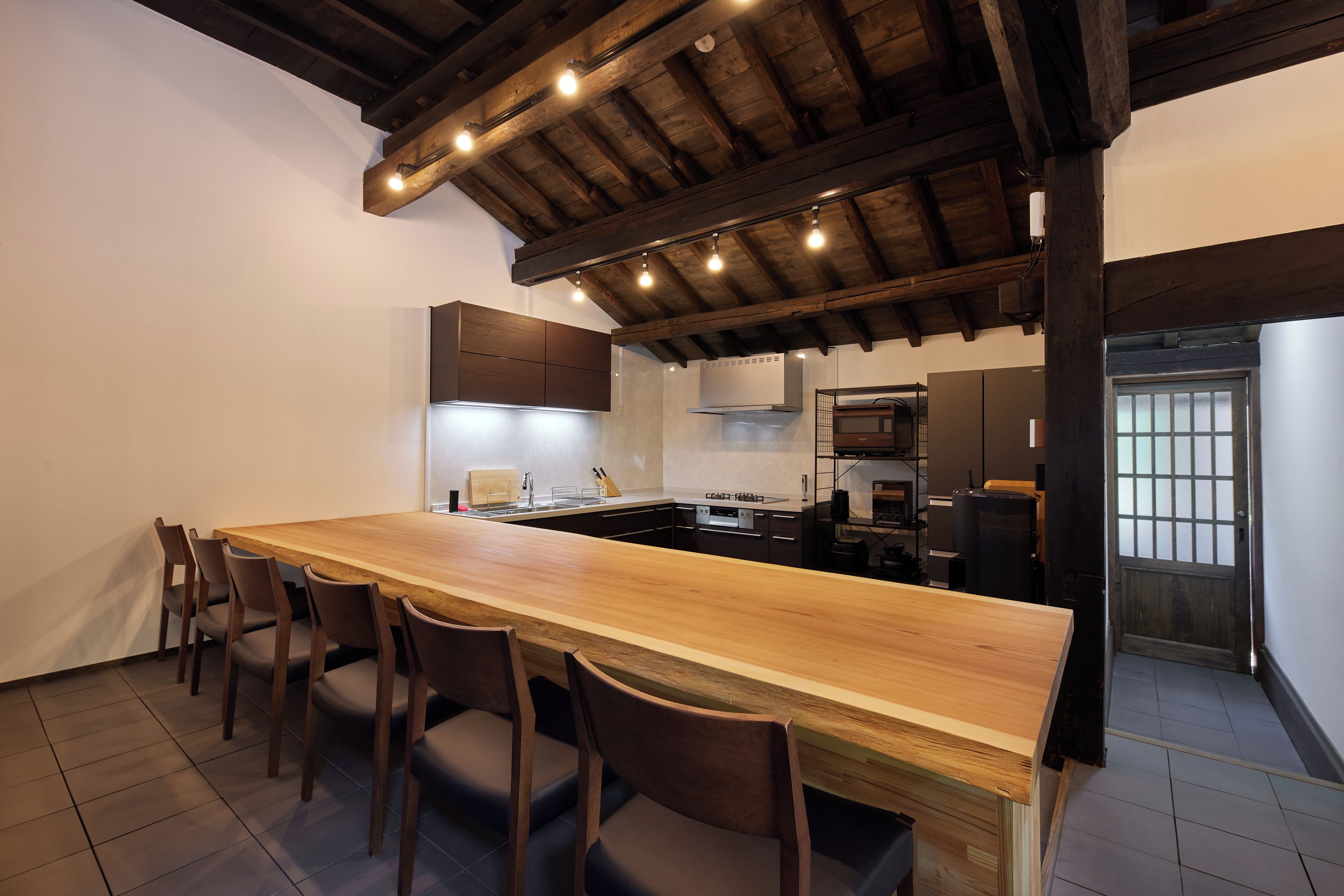 A modern kitchen with a wooden island, built-in appliances, and a dining area with chairs.