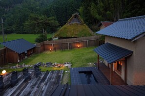 A residential property with a thatched-roof structure, a wooden deck, and a swimming pool.