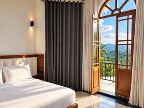 Habitación de hotel con cama, vista a un paisaje montañoso a través de una puerta abierta y un balcón con barandilla.