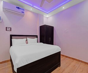 Un dormitorio con cama, armario, equipo de aire acondicionado e iluminación en el techo.