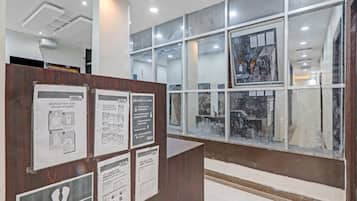 A reception area with a wooden desk, informational posters on hygiene, and a large window with artwork.