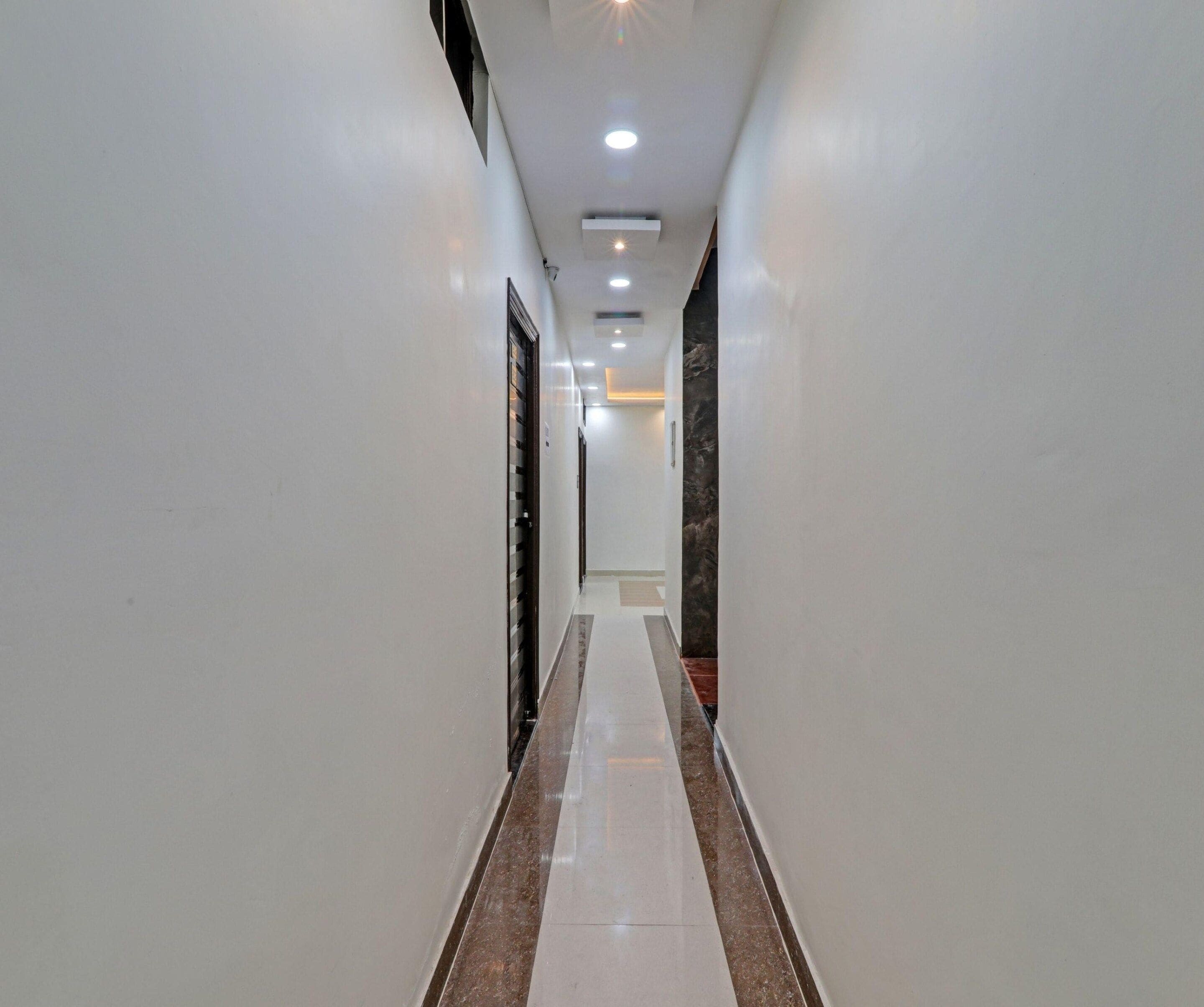 A long, narrow hallway with white walls and a marble floor.