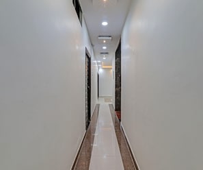 A long, narrow hallway with white walls and a marble floor. - Classic Hotel Crystal Grand (Kanpur)
