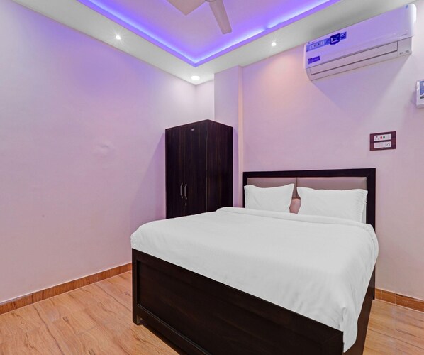 A bedroom with a bed, a wardrobe, an air conditioning unit, and a ceiling light fixture. - Classic Hotel Crystal Grand (Kanpur)