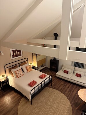 A bedroom with a bed, bedside table, lamp, and a view of a loft area. - Private bungalow in Bakkum, near Castricum aan Zee (Castricum)